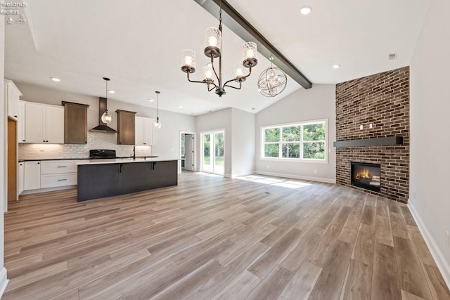 kitchen with light wood-style floors, open floor plan, range, decorative backsplash, and wall chimney exhaust hood