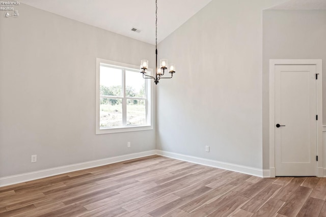 empty room with visible vents, an inviting chandelier, vaulted ceiling, light wood-type flooring, and baseboards