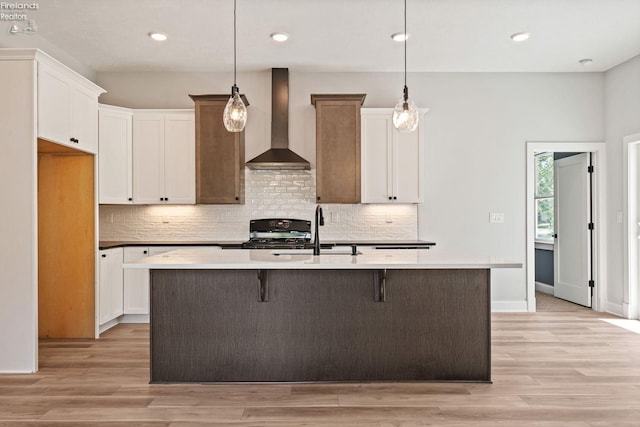 kitchen featuring wall chimney exhaust hood, a sink, range, and light wood-style floors