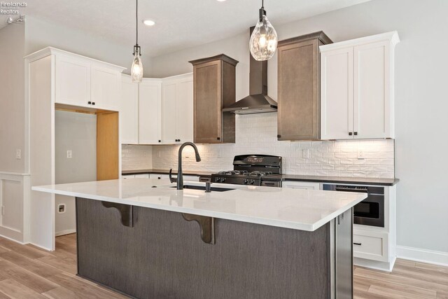 kitchen with light wood-style floors, a sink, backsplash, and black range with gas stovetop