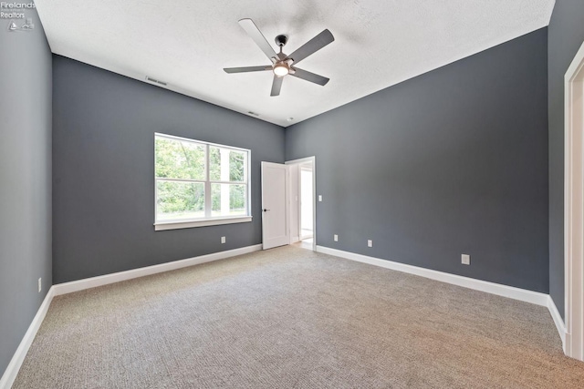 carpeted empty room featuring visible vents, ceiling fan, a textured ceiling, and baseboards