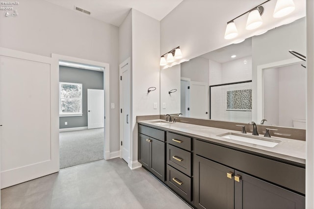 full bath with double vanity, a stall shower, baseboards, and a sink