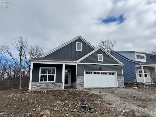 view of front of house with driveway, stone siding, and an attached garage