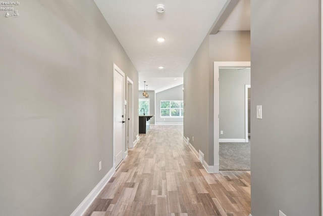 corridor with light wood-style floors and baseboards