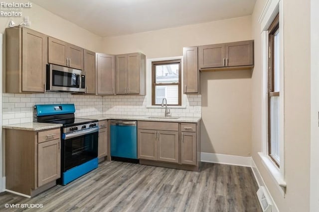 kitchen featuring light stone countertops, stainless steel appliances, light hardwood / wood-style floors, and sink