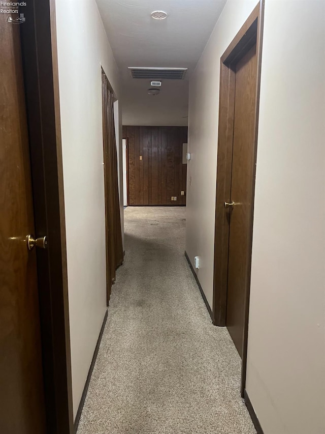 hall featuring wood walls and light carpet