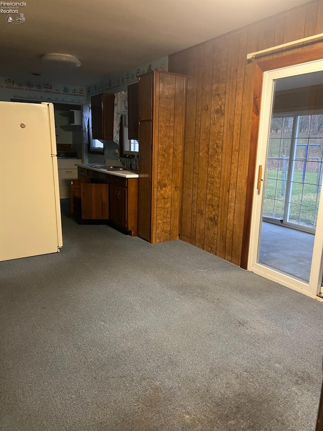 kitchen featuring wooden walls, sink, carpet floors, and white refrigerator