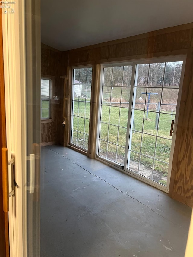 doorway with wood walls and concrete flooring