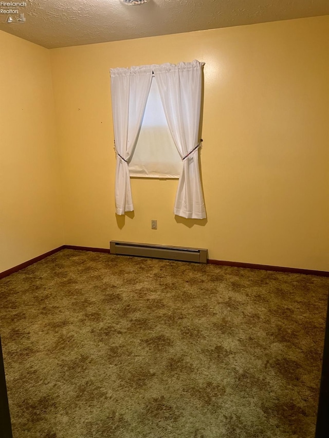 spare room with carpet flooring, a textured ceiling, and a baseboard heating unit