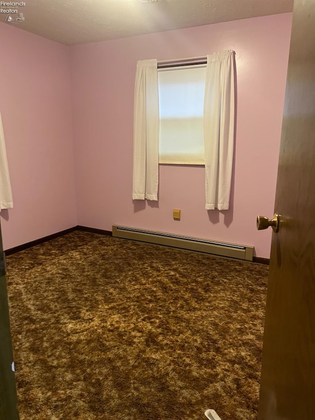 carpeted spare room with a baseboard heating unit