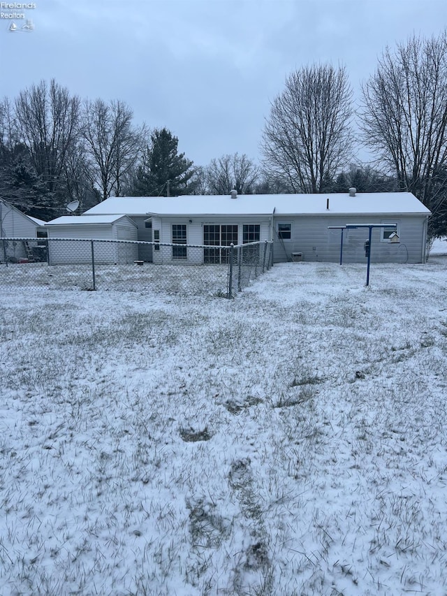 snow covered rear of property featuring a carport