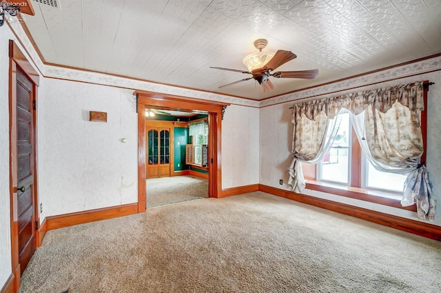 carpeted empty room featuring ceiling fan and crown molding