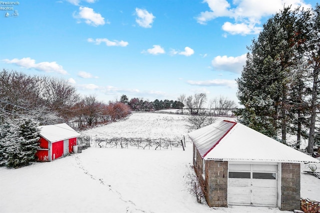 yard layered in snow featuring a garage, an outdoor structure, and central AC