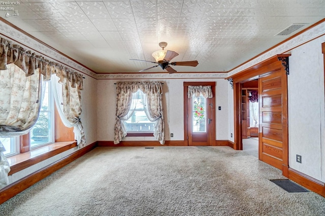 carpeted foyer featuring ceiling fan and crown molding