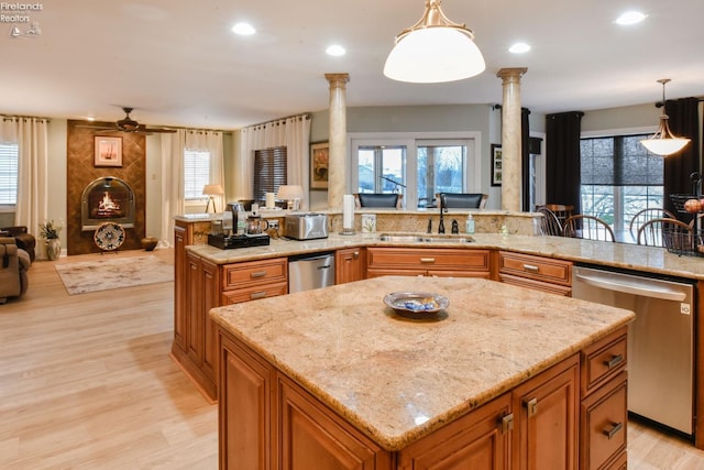 kitchen with pendant lighting, stainless steel dishwasher, sink, and decorative columns