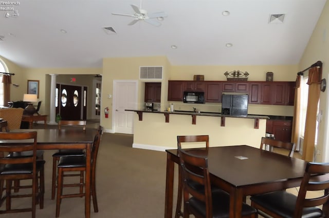 carpeted dining room with vaulted ceiling and ceiling fan