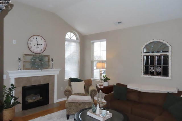 living room featuring a fireplace, vaulted ceiling, and light hardwood / wood-style flooring