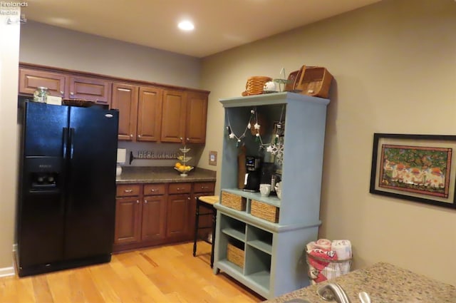 kitchen featuring light hardwood / wood-style floors and black refrigerator with ice dispenser