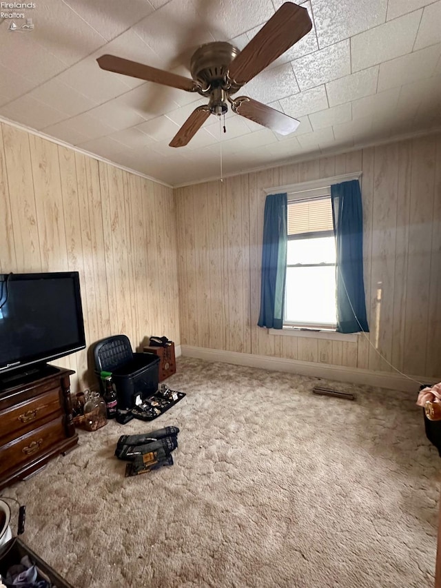 interior space with ceiling fan, carpet, and wooden walls