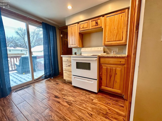 kitchen with light hardwood / wood-style floors, light stone countertops, and white range with electric stovetop