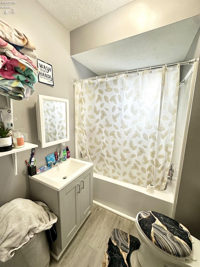 bathroom with hardwood / wood-style floors, shower / bath combination with curtain, a textured ceiling, and vanity