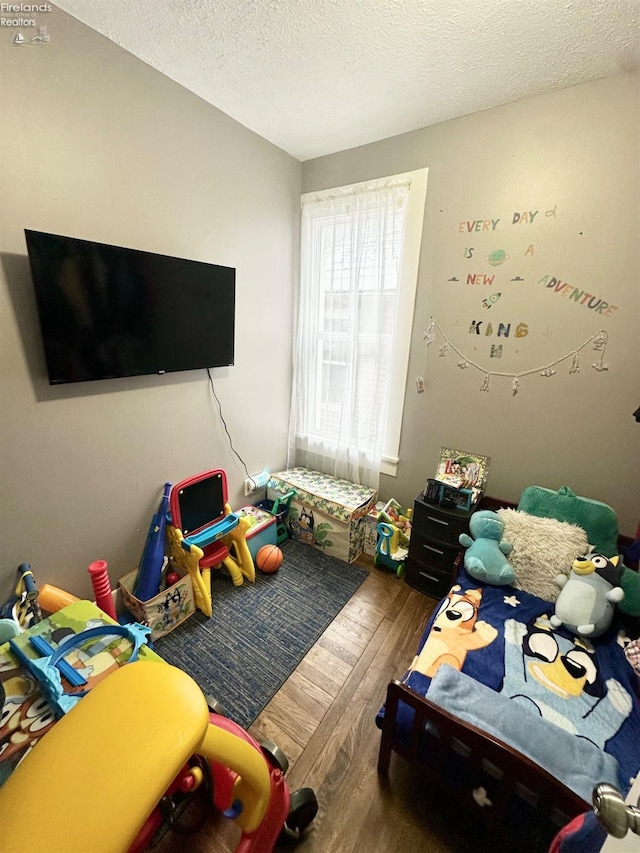 bedroom with a textured ceiling and hardwood / wood-style flooring