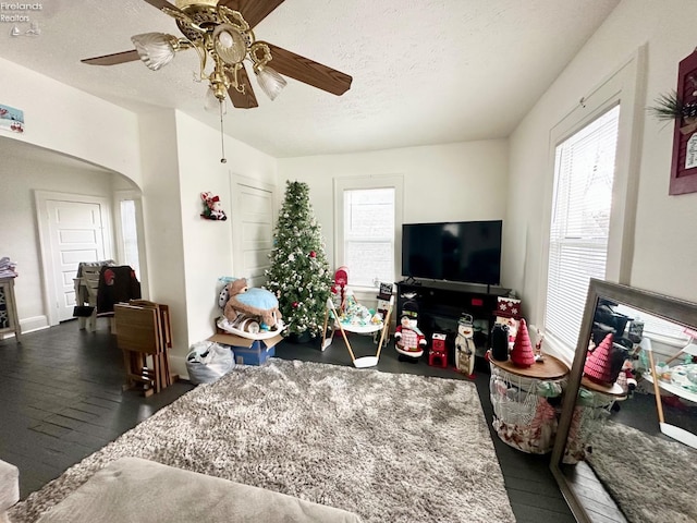 living room featuring ceiling fan, dark hardwood / wood-style flooring, and a textured ceiling