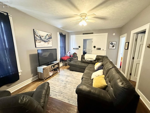 living room with ceiling fan, wood-type flooring, and a textured ceiling