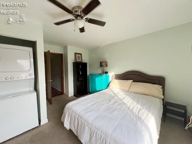 carpeted bedroom with ceiling fan and stacked washer / drying machine