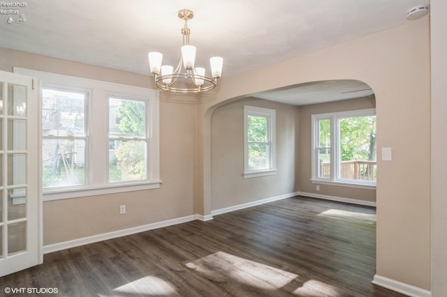 empty room with dark hardwood / wood-style floors and a notable chandelier