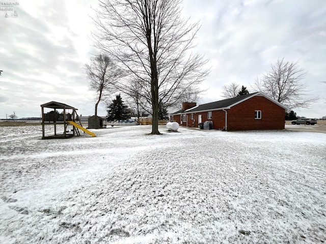 yard layered in snow featuring a gazebo and a playground