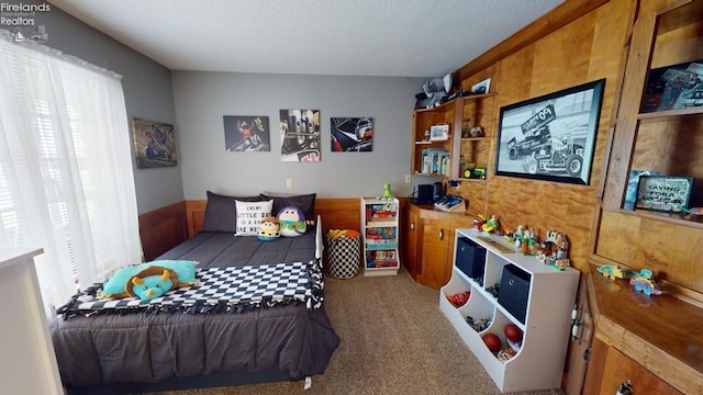 carpeted bedroom with wood walls and a textured ceiling