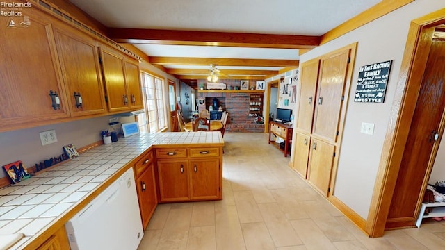 kitchen with ceiling fan, tile counters, white dishwasher, and beamed ceiling