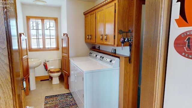 washroom featuring cabinets, sink, independent washer and dryer, light tile patterned floors, and water heater