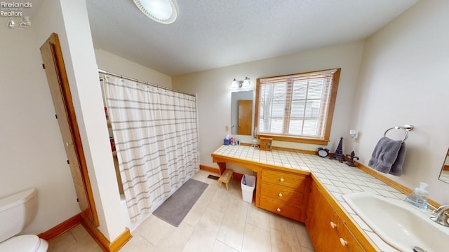 full bathroom with shower / tub combo with curtain, vanity, a textured ceiling, and toilet