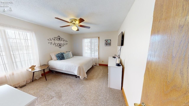 bedroom with a textured ceiling, light colored carpet, and ceiling fan