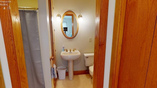 bathroom featuring curtained shower, toilet, and sink