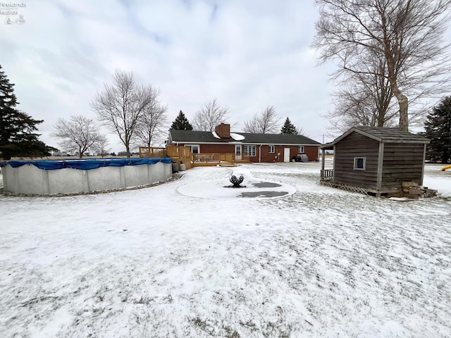 yard layered in snow featuring a pool side deck and a shed