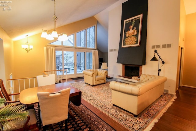 living room featuring a fireplace, high vaulted ceiling, hardwood / wood-style flooring, and an inviting chandelier