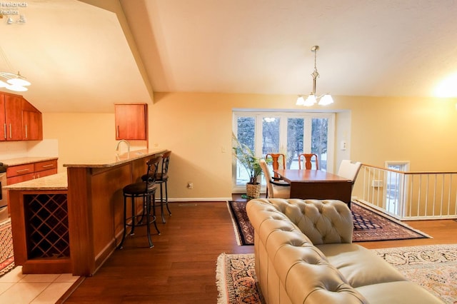 dining area featuring lofted ceiling, sink, dark hardwood / wood-style floors, and an inviting chandelier