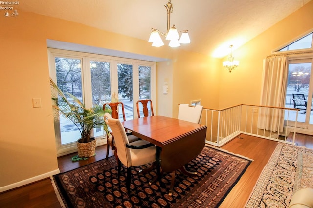 dining space featuring hardwood / wood-style floors, plenty of natural light, vaulted ceiling, and a chandelier