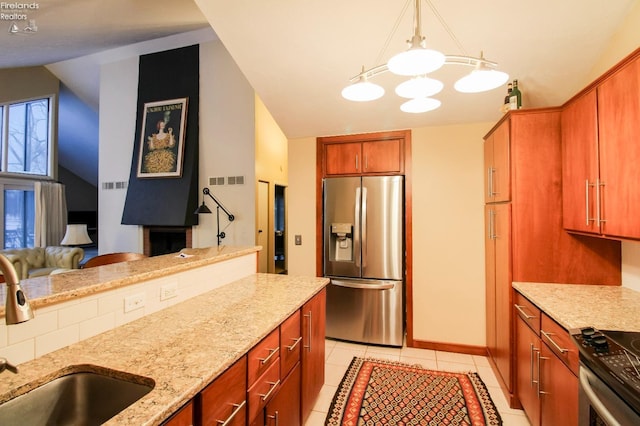 kitchen featuring sink, light stone countertops, light tile patterned floors, decorative light fixtures, and stainless steel appliances