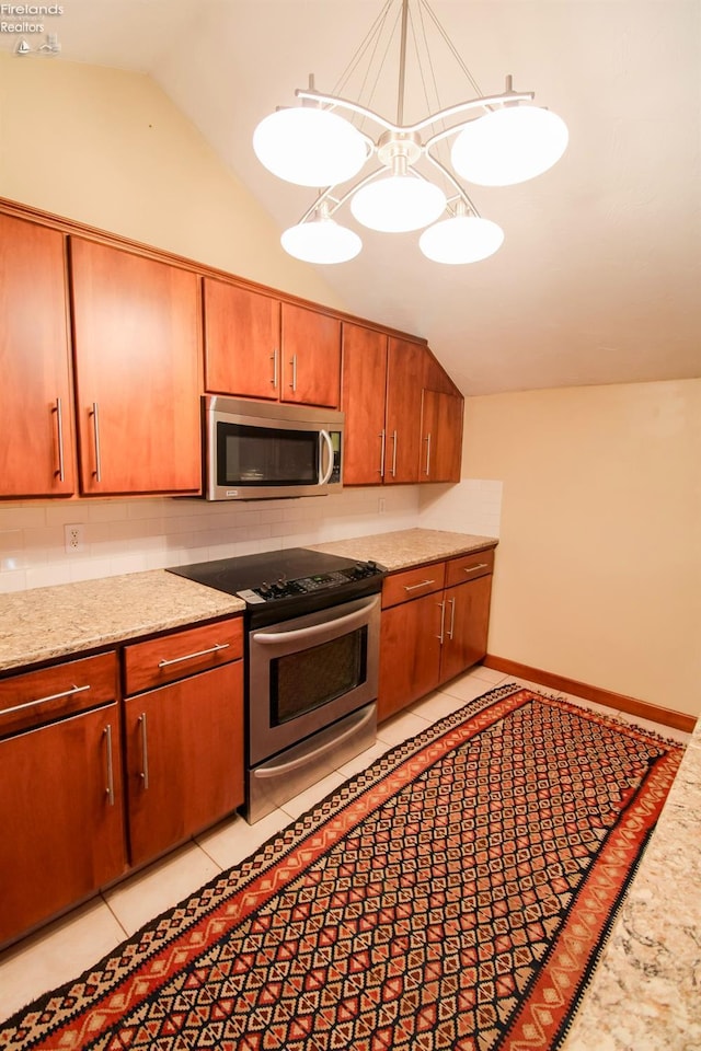 kitchen with appliances with stainless steel finishes, light tile patterned floors, vaulted ceiling, and hanging light fixtures