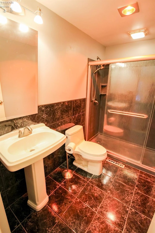 bathroom featuring a shower with door, tile walls, and toilet