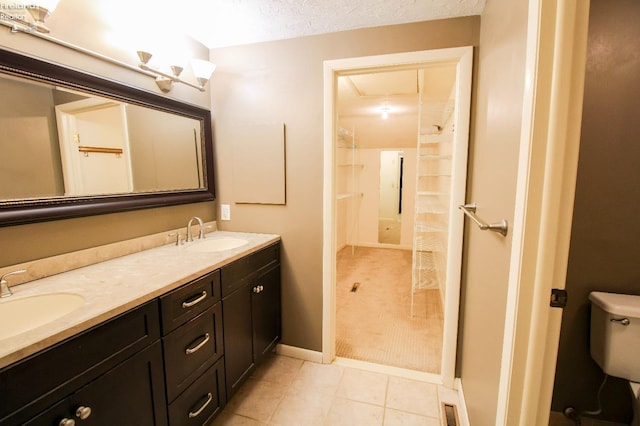 bathroom with tile patterned flooring, a textured ceiling, vanity, and toilet