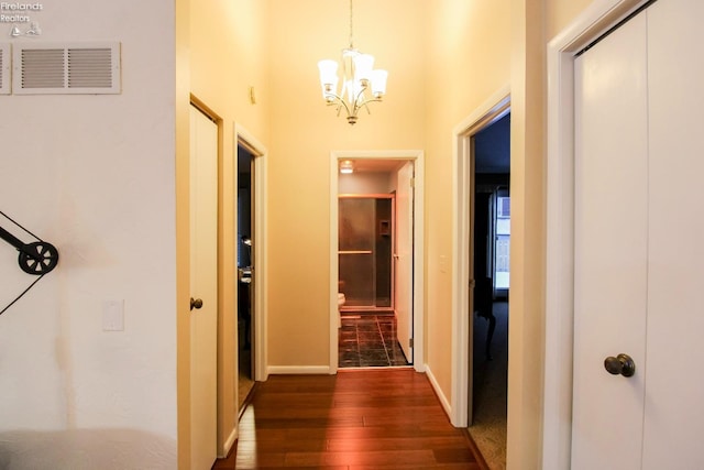 corridor with dark hardwood / wood-style floors and a notable chandelier