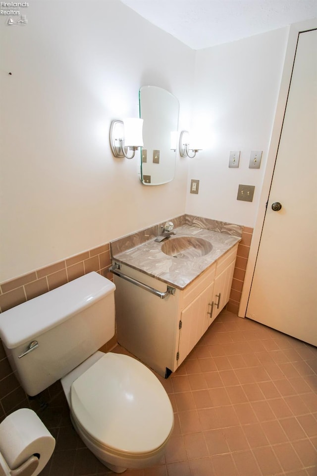 bathroom featuring tile patterned floors, vanity, toilet, and tile walls