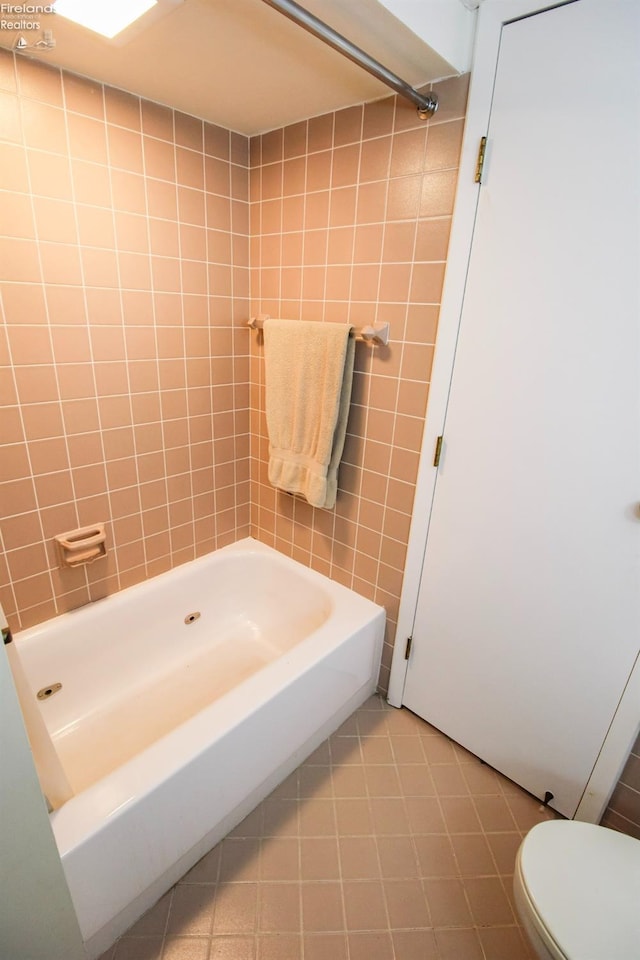 bathroom featuring tile patterned flooring, toilet, and washtub / shower combination