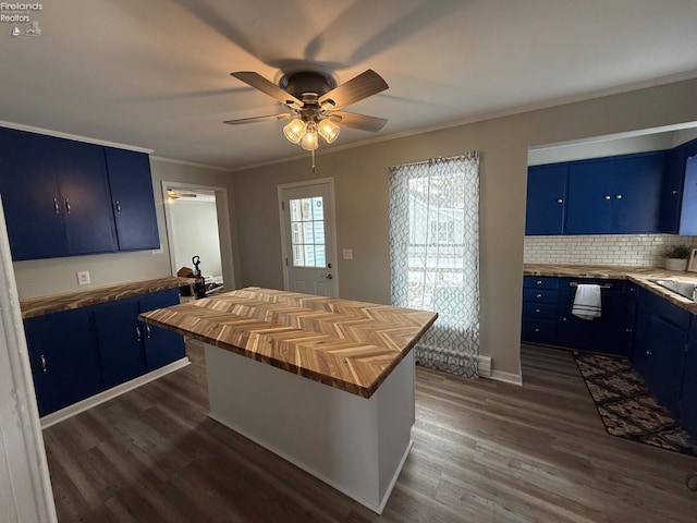 kitchen with a center island, wood counters, blue cabinetry, backsplash, and ornamental molding