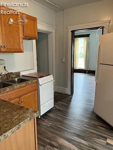 kitchen featuring white appliances, dark hardwood / wood-style floors, and sink